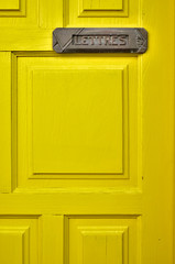 Lemon yellow door with a letter box and a French word LETTRES (English: MAIL).