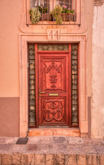 Fototapeta na wymiar A beautifully carved vintage door with a metal, glass and stone frame and a salmon wall