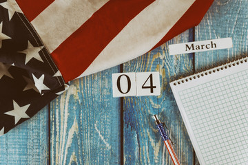 Fototapeta na wymiar 04 March calendar day Flag of the United States of America symbol of freedom and democracy with blank notepad and pen on office wooden table