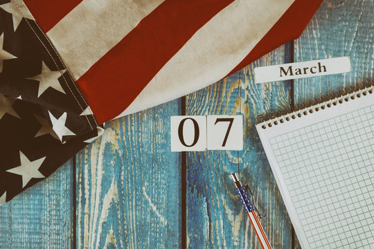 07 March calendar day Flag of the United States of America symbol of freedom and democracy with blank notepad and pen on office wooden table