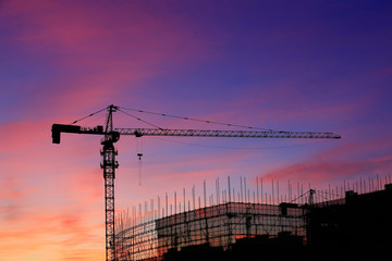 Cranes at construction sites, silhouetted at sunrise