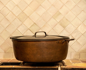 Side view of an old copper cooking pan or casserole pot on kitchen counter
