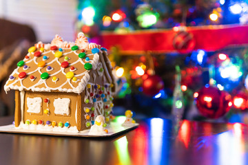 Gingerbread house in front of Christmas Tree with lights on