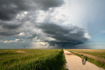 A man photographing a supercell storm in wheat field