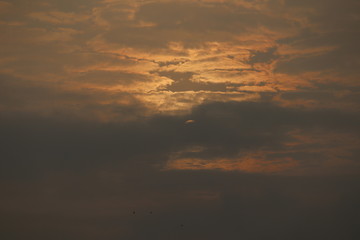 MORNING SUN SHINING BEHIND THE CLOUDS