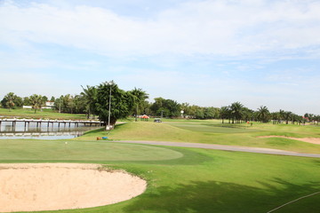 Obraz premium Sand bunker on the golf course with green grass and trees over blue sky. 