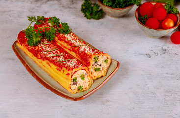Italian food cannelloni with ricotta and tomato sauce.