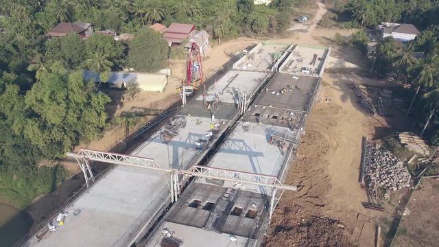 fly back over the new bridge under construction. Pump truck that sent cement through a long of aerial pipe to reach the foundation as backdrop
