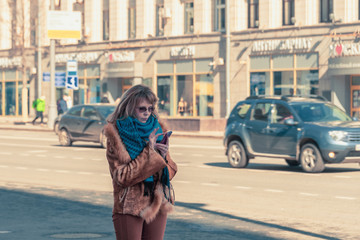 Obraz premium A woman with a smartphone in hands stands on a city street