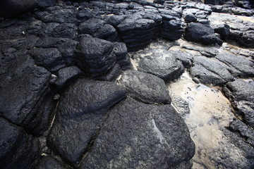 Black lava rock mosaic on Hawaiian shore