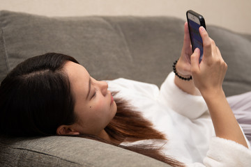 Obraz na płótnie Canvas 寝転がって携帯を操作する女性