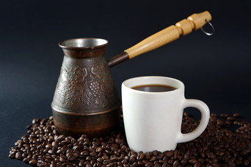 A Cup of coffee and Turkish coffee pot among the coffee beans