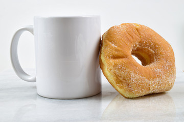 Fresh sugar donut resting against white coffee cup