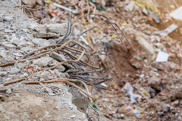 Rebar from the old building demolished. The rebar sticking up from piles of brick rubble, stone and concrete rubble against. Remains of the destroyed building.