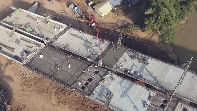 rotating drone shot of the pump truck that sent a mixture of cement, sand, gravel and water through a long of aerial pipe to reach the foundation of the new bridge