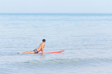Handsome guy lying on surfboard on water