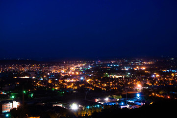 Fototapeta na wymiar Night cityscape of many buildings and lights. Classic blue dark sky at evening