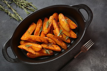 Baked, fried potato wedges with spices and rosemary. Roast potatoes with spices in the frying pan