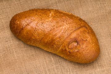 Fresh rye loaf of bread on sackcloth, rustic style.
