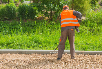 male worker equals rake with gravel