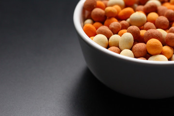 Peanuts with a crispy crust around it in a white bowl. Copy space for text.