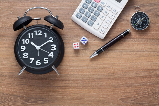 Conceptual,alarm clock,dice,pen,calculator and compass on wood background