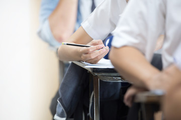 high school,university student study.hands holding pencil writing paper answer sheet.sitting lecture chair taking final exam attending in examination classroom.concept scholarship for education abroad