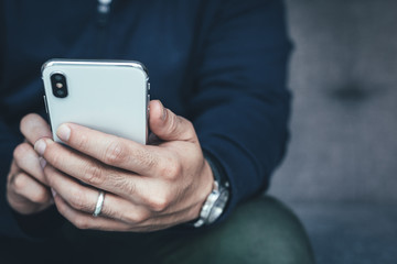 using cell phone.hand holding texting message on screen mobile chatting friend ,search internet information sitting on sofa in office.technology device contact communication connecting people concept