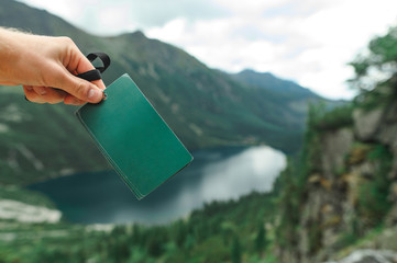 Man's hand holds a blank green turgid against the background of Lake Morskie Oko, or Eye of the Sea...