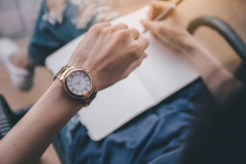 looking at luxury watch on hand check the time writing business information in notepad at...