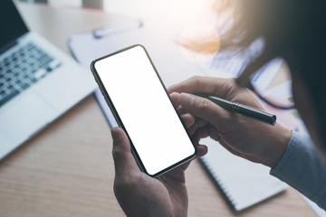 Mockup image blank white screen cell phone.man hand holding texting using mobile on desk at home office.background empty space for advertise text.people contact marketing business,technology 