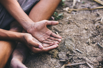 hands poor child or beggar begging you for help sitting at dirty slum. concept for poverty or...