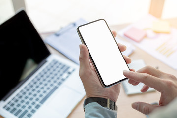 Mockup image blank white screen cell phone.man hand holding texting using mobile on desk at home office.background empty space for advertise text.people contact marketing business,technology 
