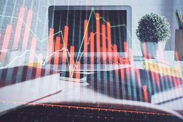 Stock market graph on background with desk and personal computer. Double exposure. Concept of financial analysis.
