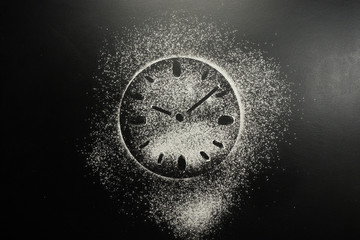 Drawing flour on a black board. Clock