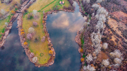 Drone shot of cozy little lake with beautiful colors in the middle of lake on an island