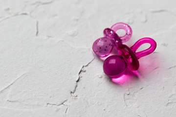 two pink pacifiers on a white background