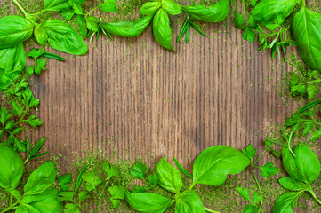 Fresh basil and parsley on wooden background top view.