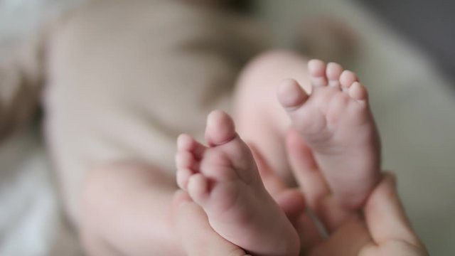 Touching baby feet softly with tender love in slow motion closeup