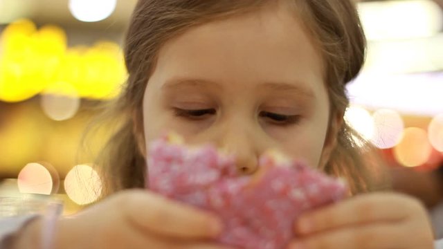 Child eats donut. Closeup baby girl eating doughnut with glase. Delicious, sweet, sweettooth.