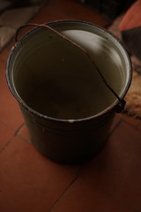 old bucket of water with metal handle on the floor.