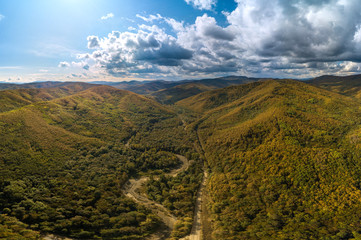 panorama of the forested low mountains of the Western Caucasus at the very beginning of autumn -...