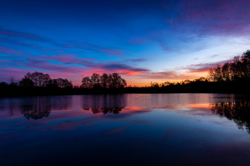 Fototapeta premium Sunset at czech countryside lake. Dramatic clouds.