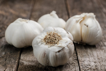 Knoblauch (lat. Allium sativum) auf rustikalem alten  Holztisch