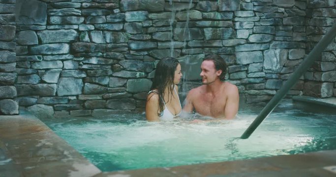 Happy diverse attractive couple enjoying a spa hot tub together, romantic couple enjoying a hot tub on vacation