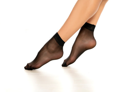 Female legs in black short nylon socks on white background