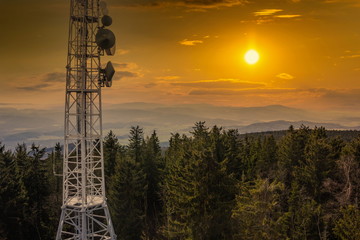 Telecommunications tower, antenna and satellite dish over Sumava forest.