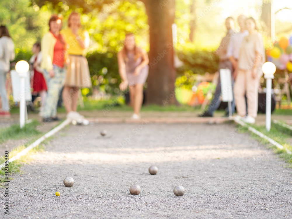 Wall mural friends playing petanque woman throwing a ball outdoor city park