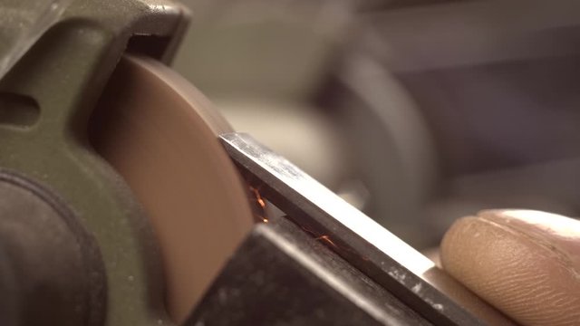 a carpenter grinds a chisel on a grinder. macro 4k