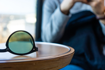 Sunglasses on a table with a person in background